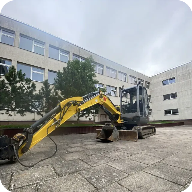 Wacker Neuson ekskavatorius aplinkos tvarkymo darbuose prie visuomeninio pastato